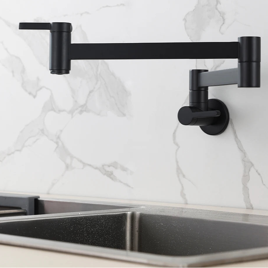 A matte black wall-mounted kitchen faucet with an adjustable arm and side lever, installed above a stainless steel sink against a white marble backsplash. The brand name PESI is visible in the top left corner.