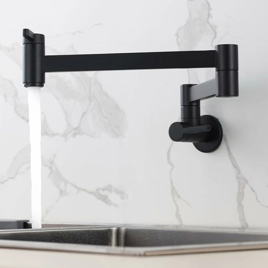 PESI matte black wall-mounted kitchen faucet with an adjustable arm and spout, shown with water flowing into a stainless steel sink against a white marble backsplash.