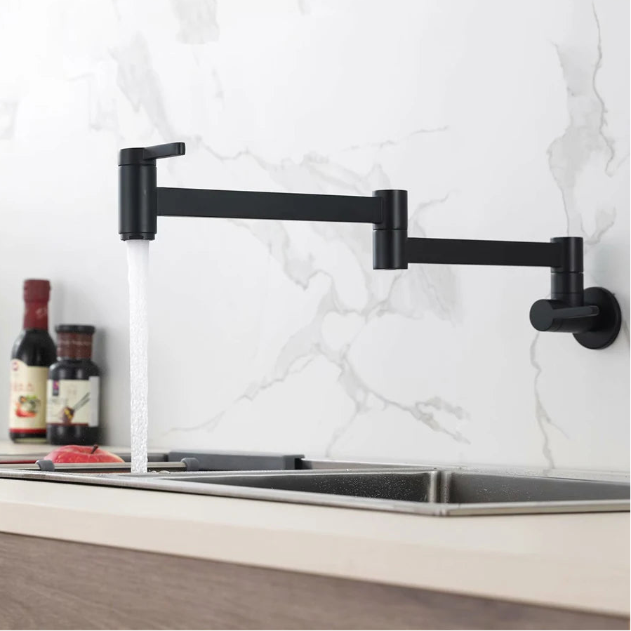 A black wall-mounted adjustable kitchen faucet with water running, installed above a double sink in a modern kitchen with a white marble backsplash. The brand name PESI is visible in the top left corner.