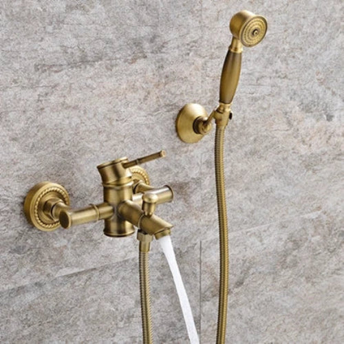 Gold bathroom faucet with handheld shower head on a tiled wall