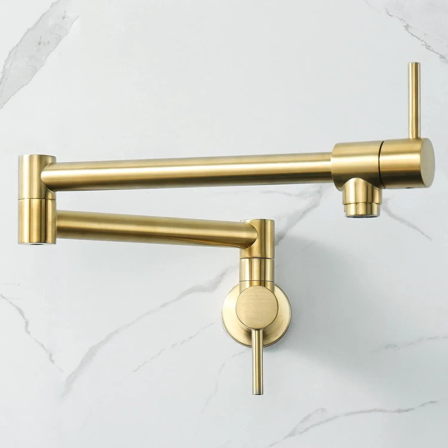 Gold kitchen faucet mounted on a white marble wall