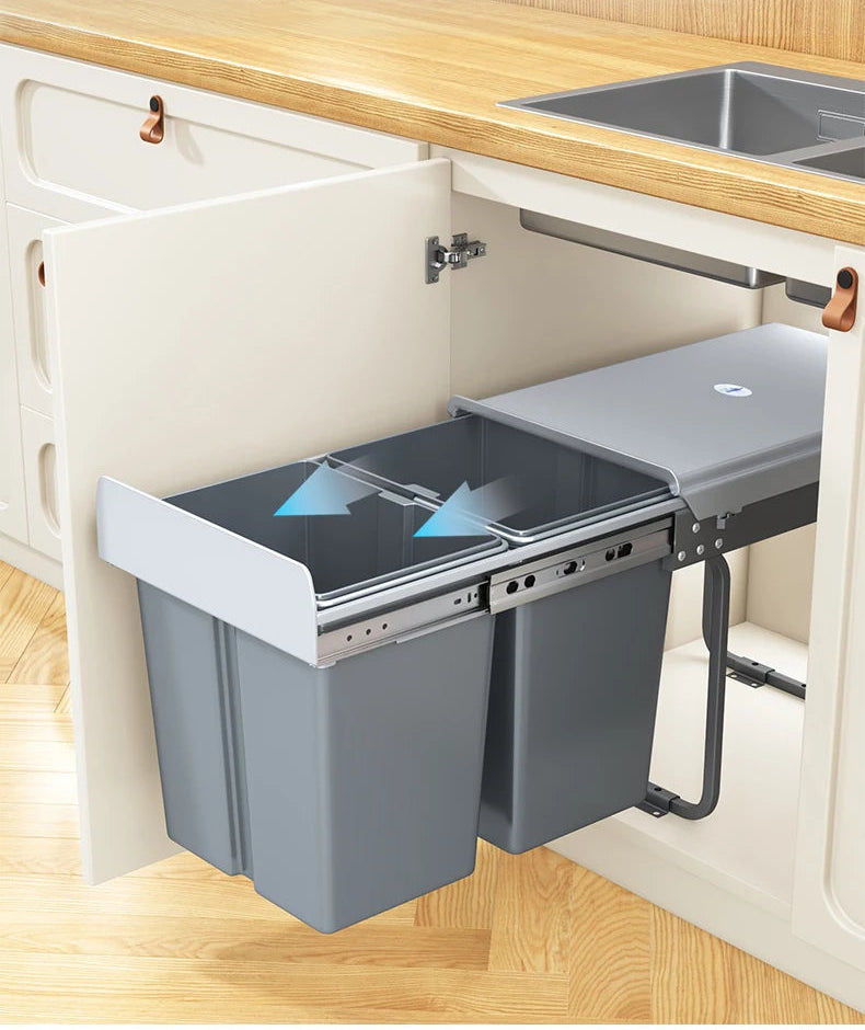 A pull-out under-counter kitchen trash bin with a gray container and dark lid, shown installed beneath a wooden countertop. The image includes Chinese marketing text at the top and blue arrow graphics indicating the lid closes automatically.