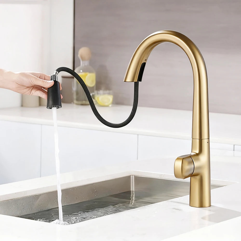 Gold kitchen faucet with a pull-out hose being used over a sink.