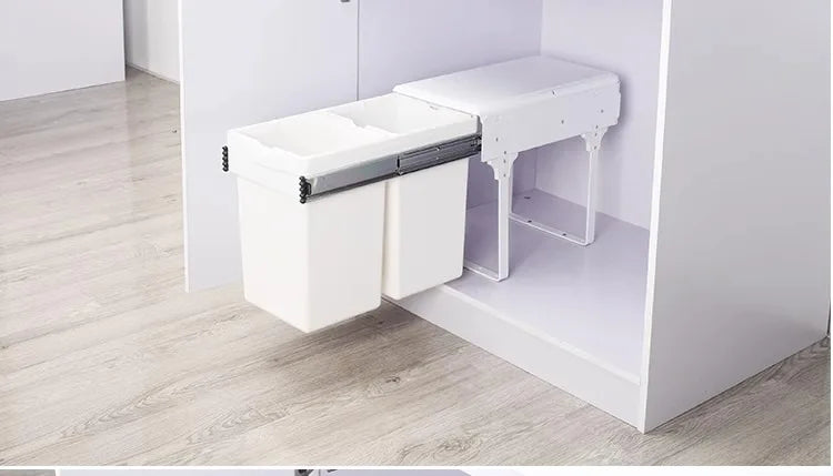 White cabinet with a pull-out trash bin in a minimalistic setting.