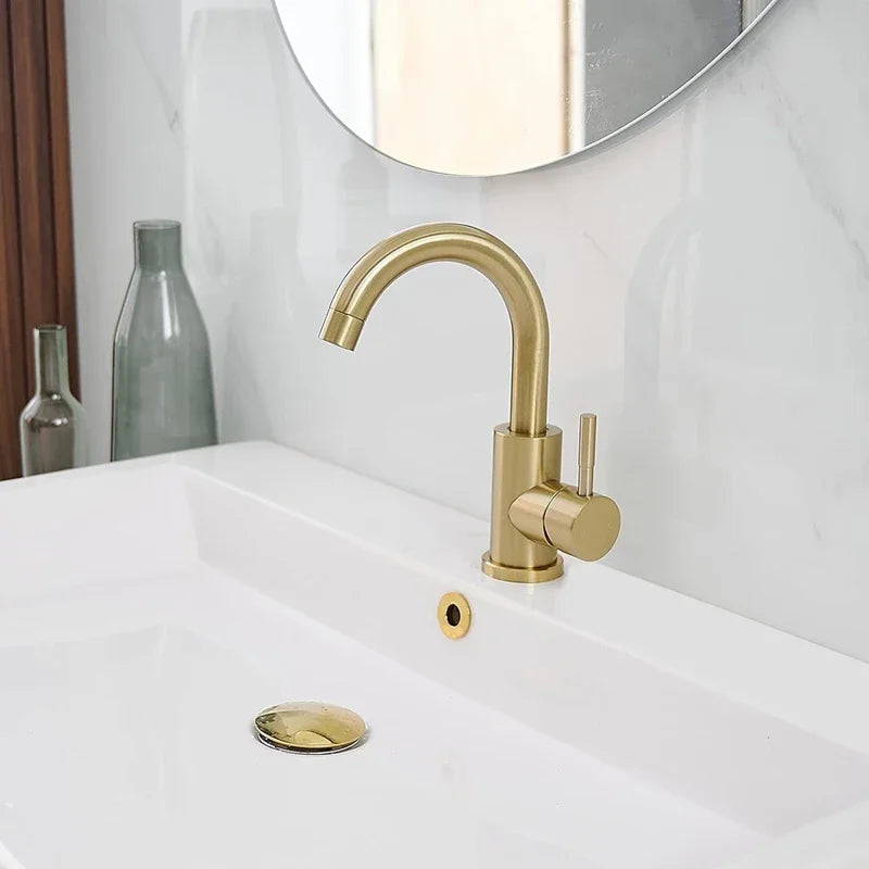 Gold faucet on a white sink with a mirror in the background