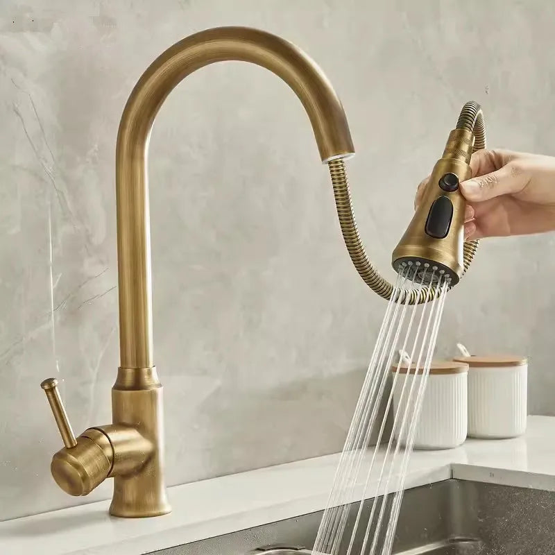 Gold kitchen faucet with a handheld shower head in a kitchen setting.