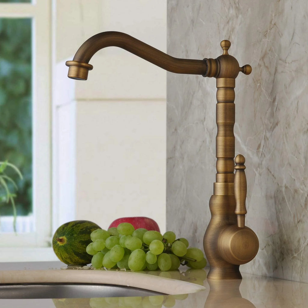 Bronze kitchen faucet on a marble countertop with grapes and a watermelon.