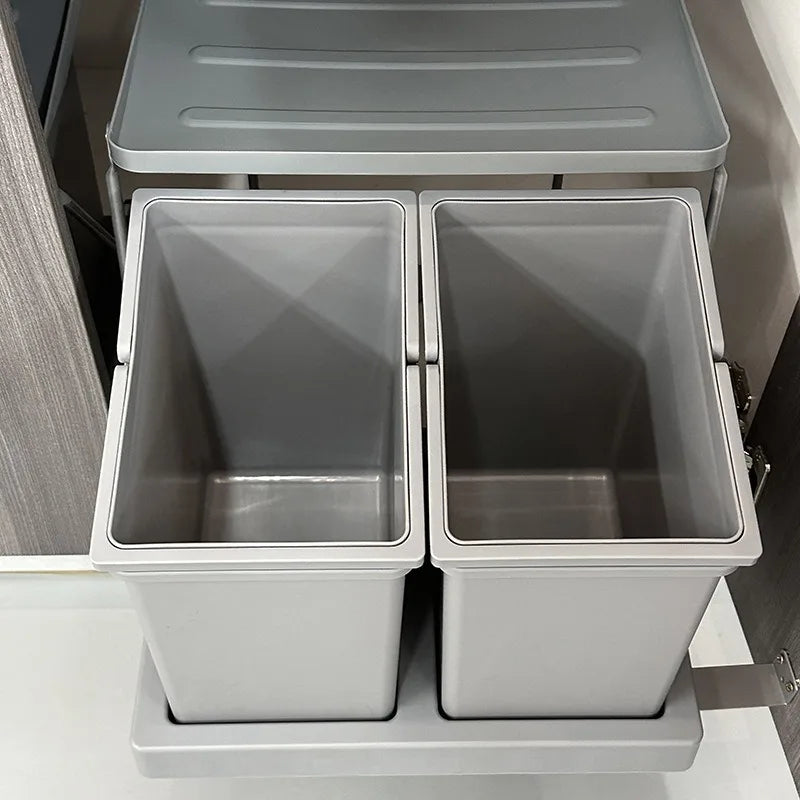 Set of three metallic trash bins with lids on a wooden floor.