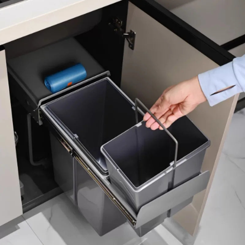 Person opening a kitchen cabinet with a pull-out trash bin.