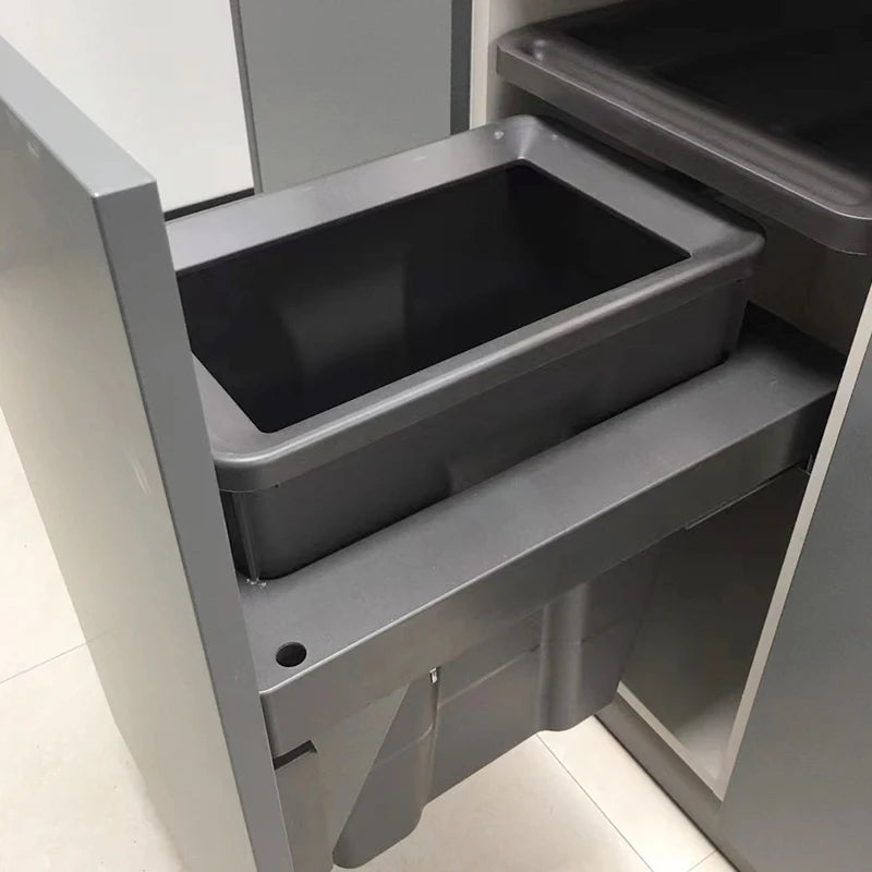 Grey cabinet with a pull-out trash bin on a tiled floor.