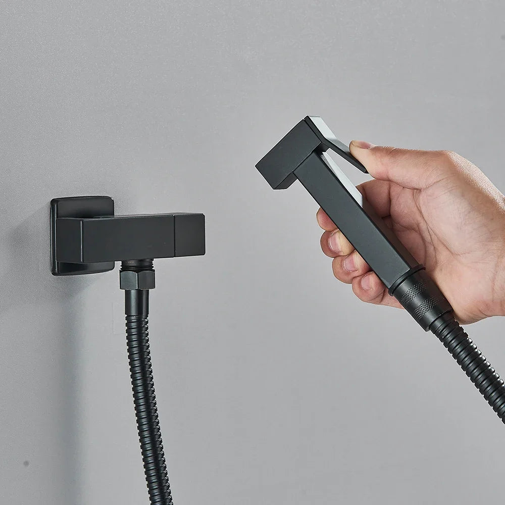 Hand holding a black shower head with a flexible hose against a gray background
