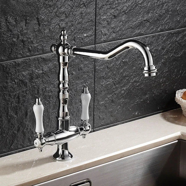 Chrome kitchen faucet with white ceramic handles on a black tiled wall background