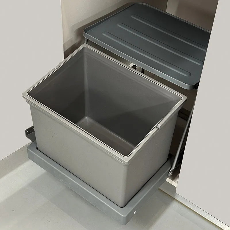 Grey trash bin with lid in a kitchen cabinet