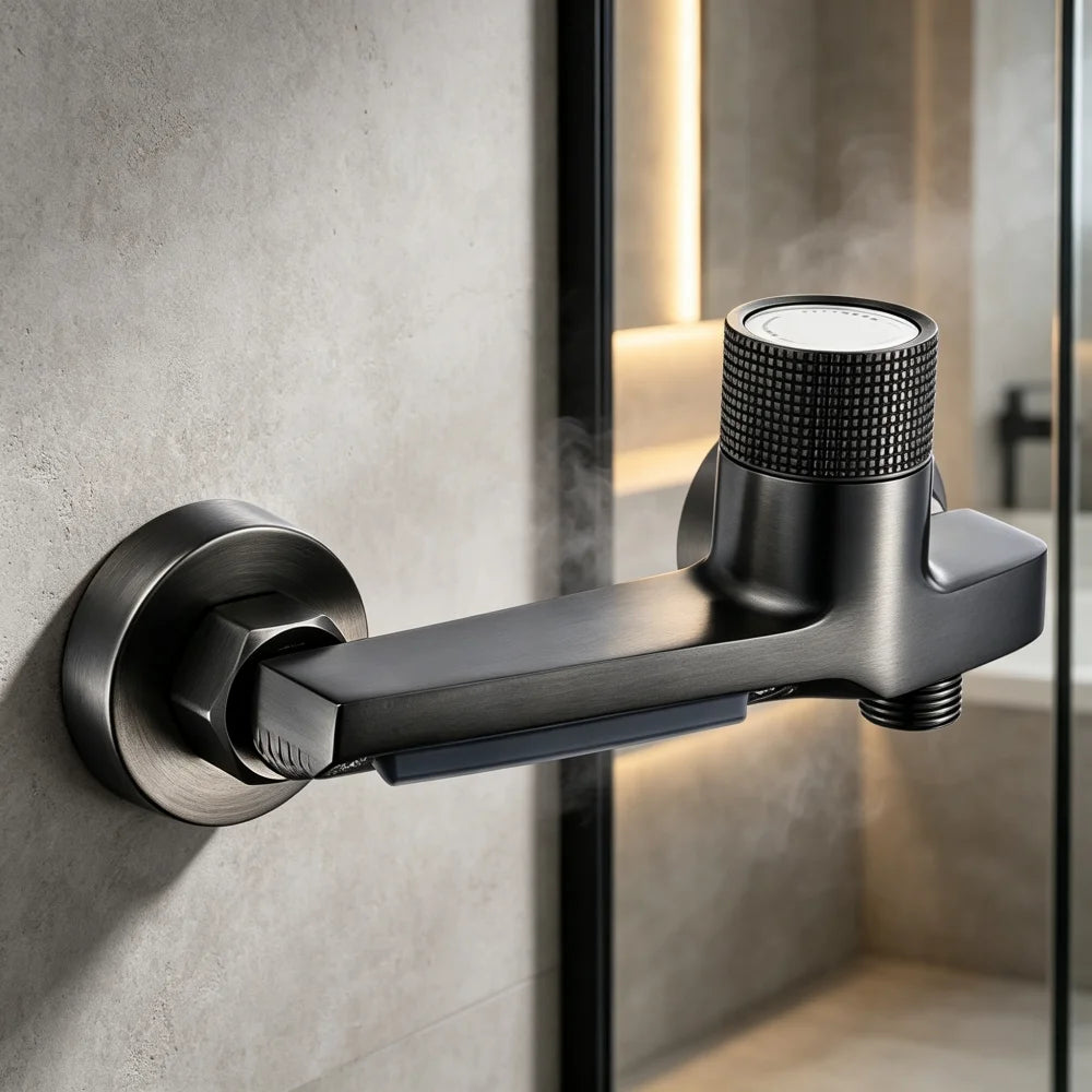 A matte black wall-mounted shower arm with a textured dial handle and a blue temperature indicator strip, shown mounted on a gray concrete-textured wall next to a glass shower door.