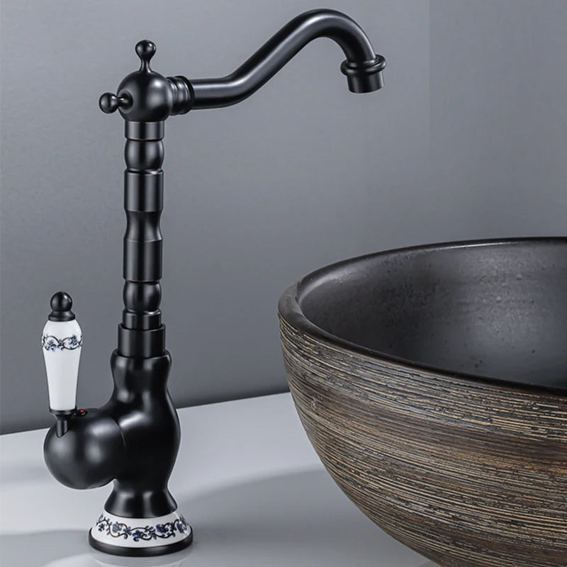 Black faucet with decorative elements next to a round black sink on a gray background