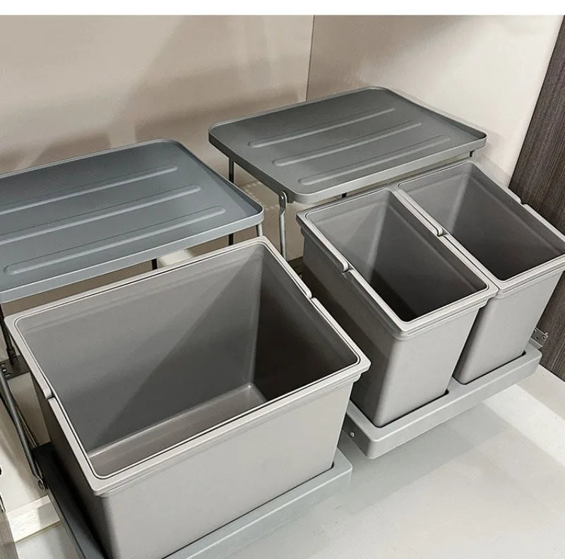 Four grey plastic drawer organizer bins with matching lids, shown partially extended inside a white drawer or cabinet.