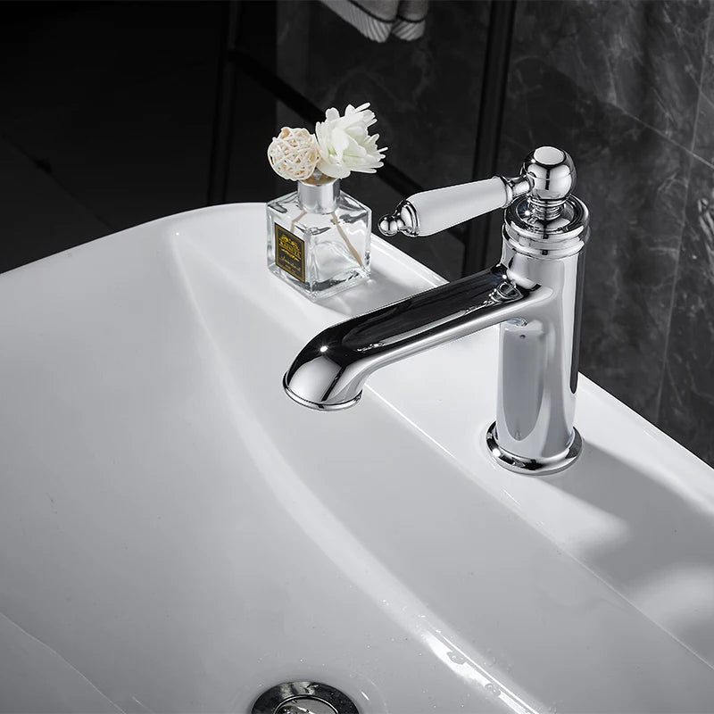 Chrome faucet on a white sink with a small vase of flowers.