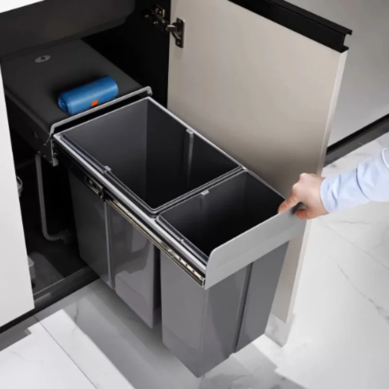 Person opening a cabinet with a trash bin inside