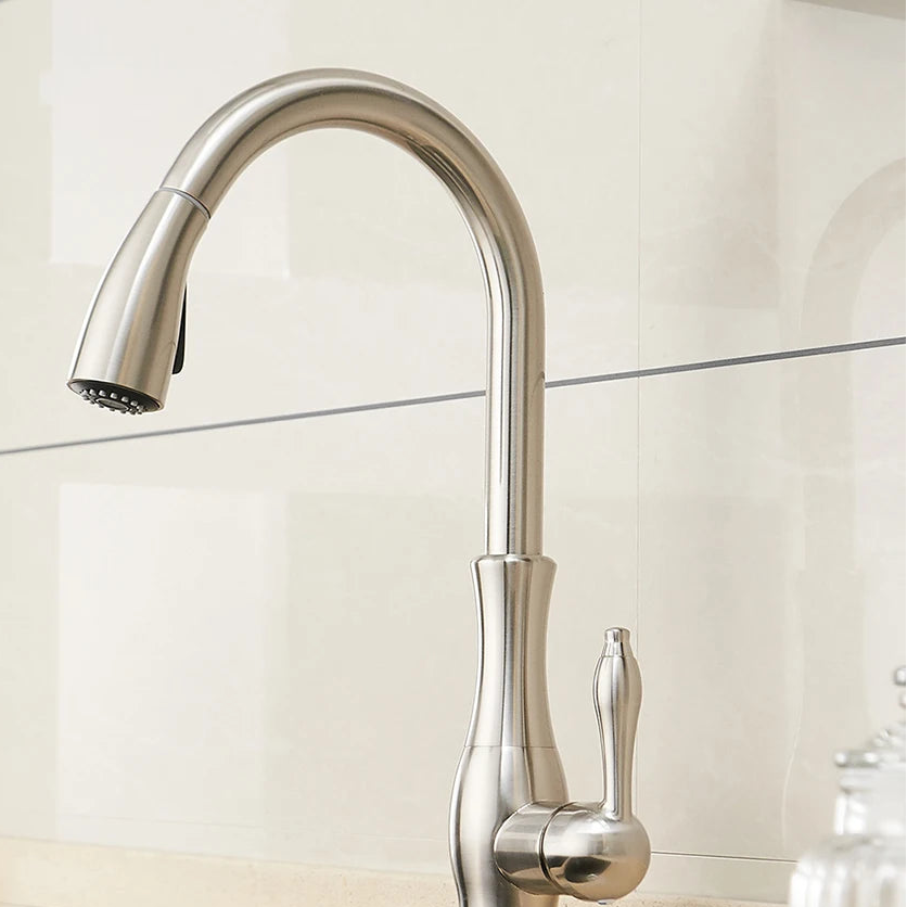 Brushed nickel kitchen faucet against a light tiled wall