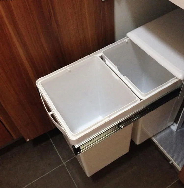 White trash bin with two compartments attached to a kitchen cabinet.